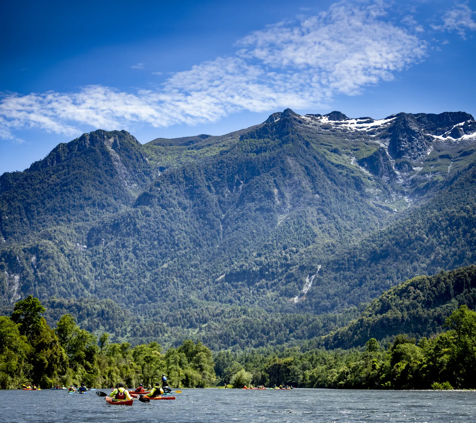Kayakistas en el Río Calcurrupe con volcán nevado de fondo, Futrono
